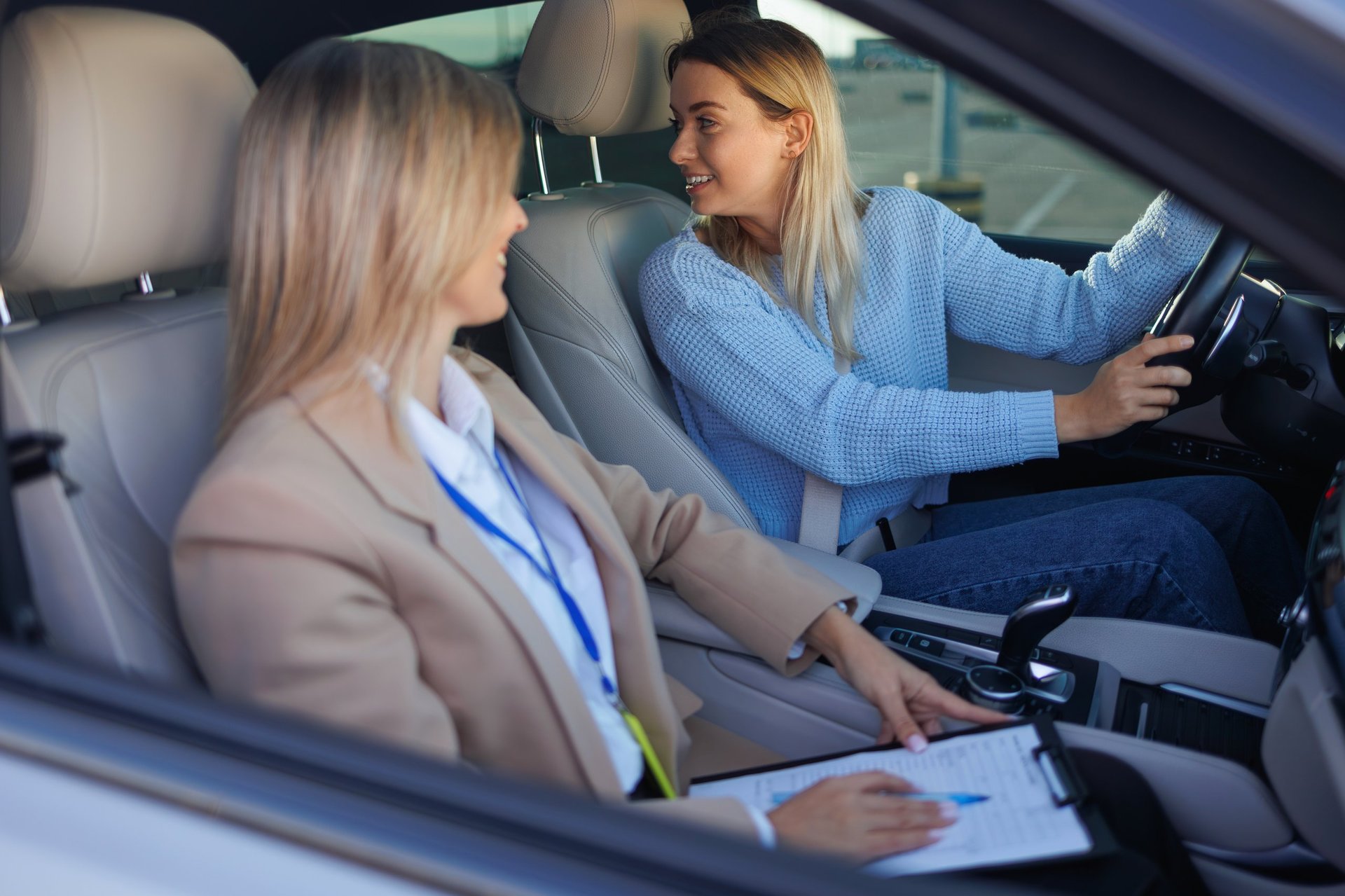 Learner Driver Turning Steering Wheel While Talking to Instructor During Practical Lesson